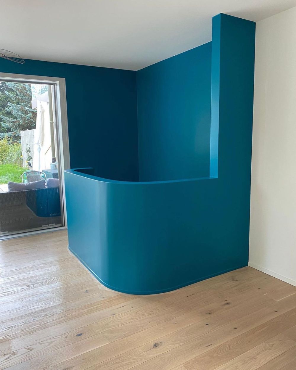 Mur arrondi peint en bleu canard avec finition soignée et parquet en bois clair – Travaux de peinture et décoration intérieure par AK Rénovation dans le Pays de Gex